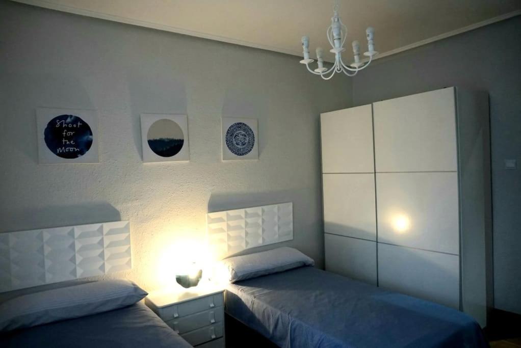 1 dormitorio con 2 camas y lámpara de araña en Apartamento centro Barakaldo BEC, en Barakaldo