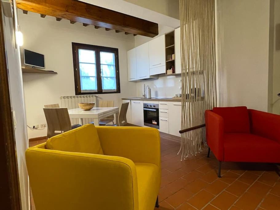 un salon avec un canapé jaune et un fauteuil rouge dans l'établissement Appartamento in Villa storica con parco e piscina, à Montelupo Fiorentino
