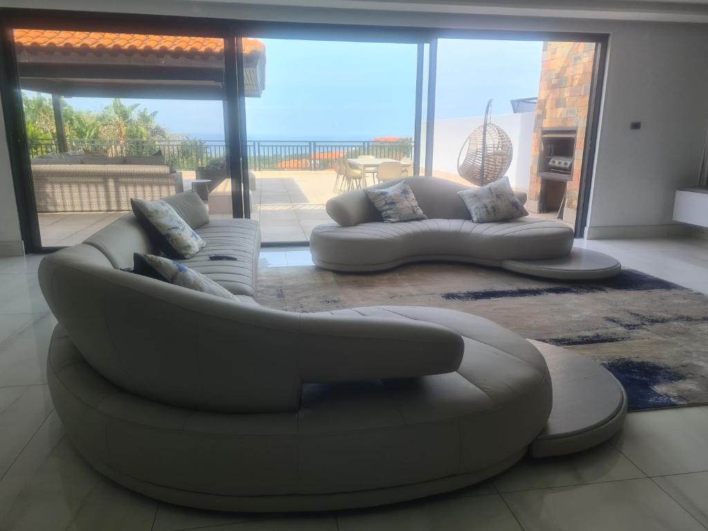 a living room with two couches and a view of the ocean at Zimbali 20 Phezulu Villa in Ballito