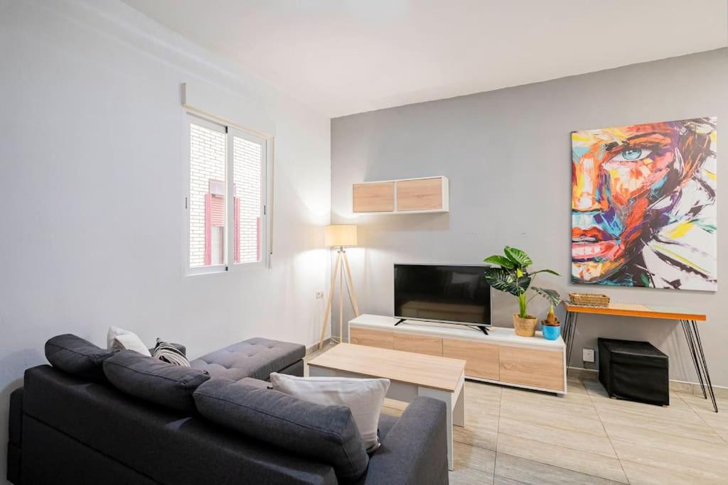 a living room with a black couch and a tv at Tranquilo apartamento en Principe Pío/Pza de España FLOR in Madrid