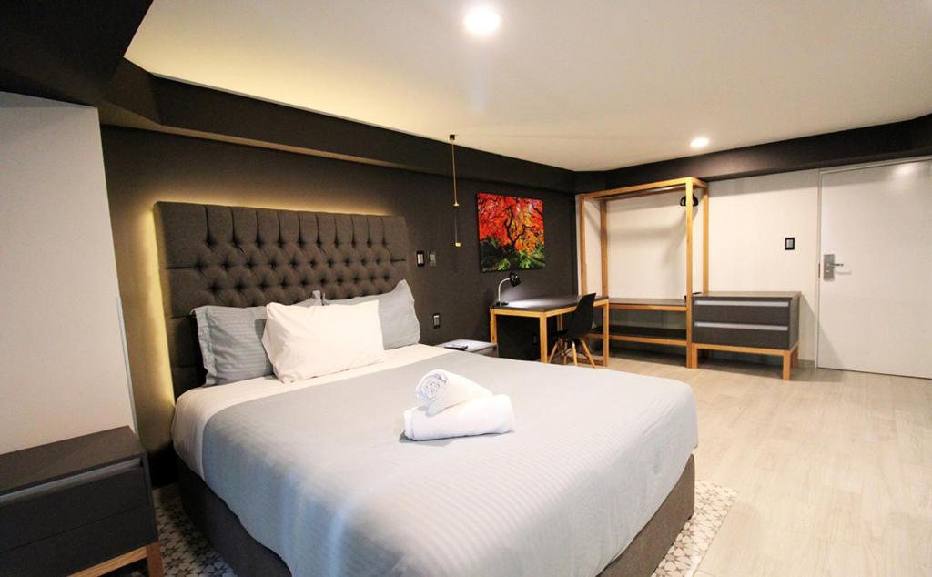 um quarto com uma cama grande e uma toalha branca. em Casa Romita em Cidade do México