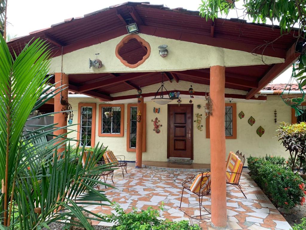 ein Haus mit einer Terrasse mit Stühlen davor in der Unterkunft Sunrise Hostel Farallon in Río Hato