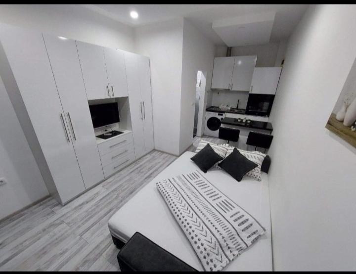 a white room with a bed and a kitchen at Apartman Fortuna in Banja Luka