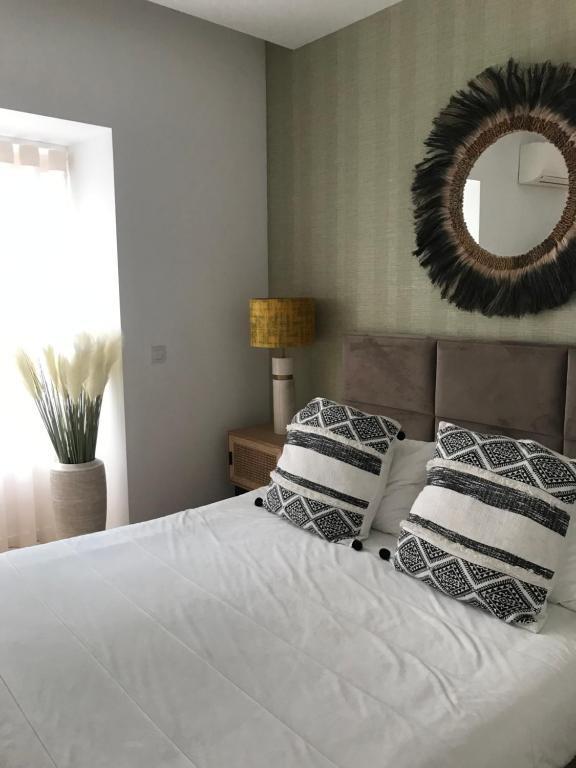 a bedroom with a bed with pillows and a mirror at Aveiro Garden's Home in Aveiro