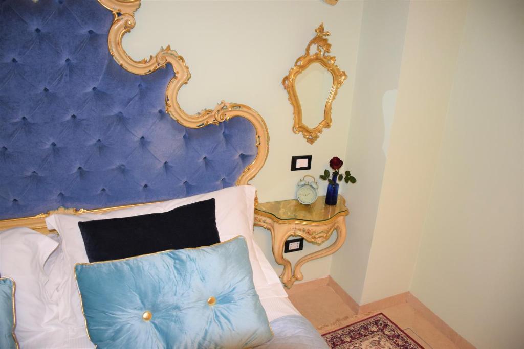 a bed with a blue headboard and a mirror at Le Pizzocchere in Venice