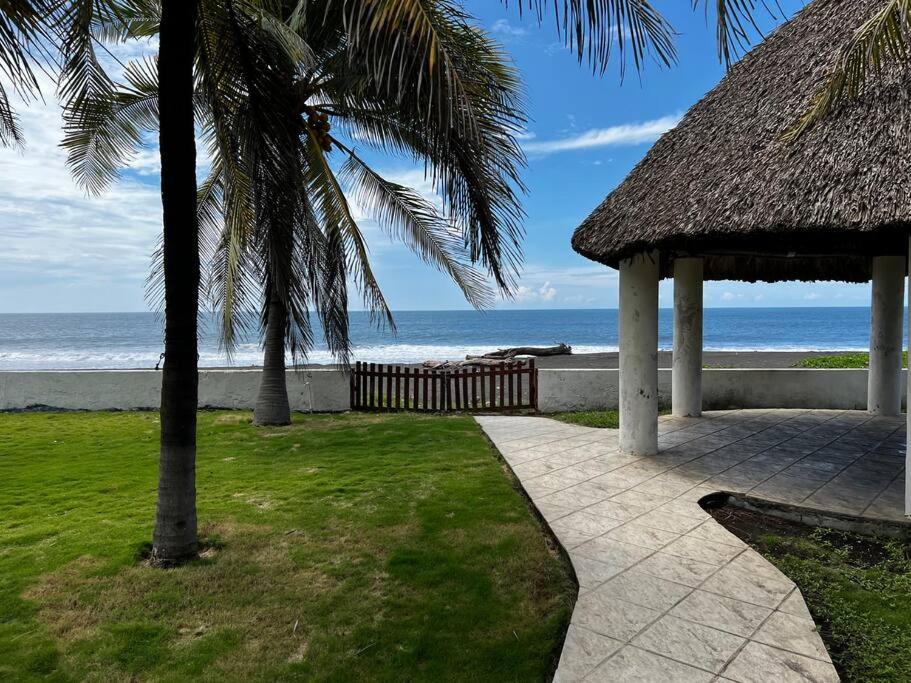 een loopbrug naar een strand met een rieten dak bij Monterrico Casablanca in Chiquimulilla