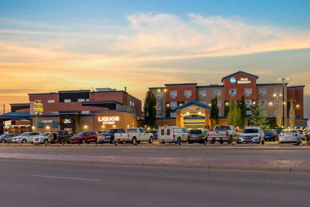 a parking lot with cars parked in front of buildings at Best Western Cold Lake Inn in Cold Lake