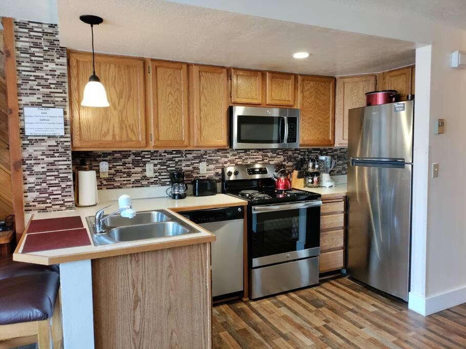 a kitchen with stainless steel appliances and wooden cabinets at Alex's Cozy STUDIO with Pool and Sauna in Brian Head