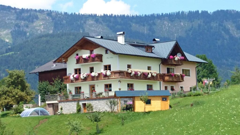 ein Haus auf einem Hügel mit Blumen auf den Balkonen in der Unterkunft Biohof Haus Wieser in Abtenau