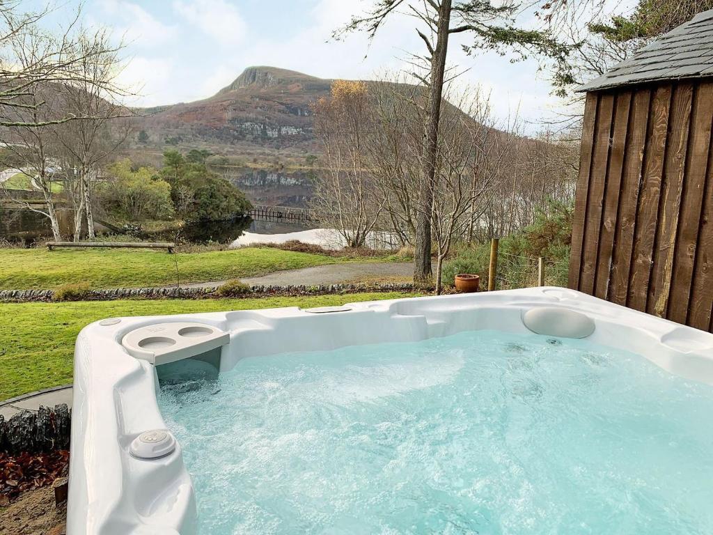 una bañera de hidromasaje en un patio trasero con vistas a la montaña en Sluice Keepers Cottage en Skelbo