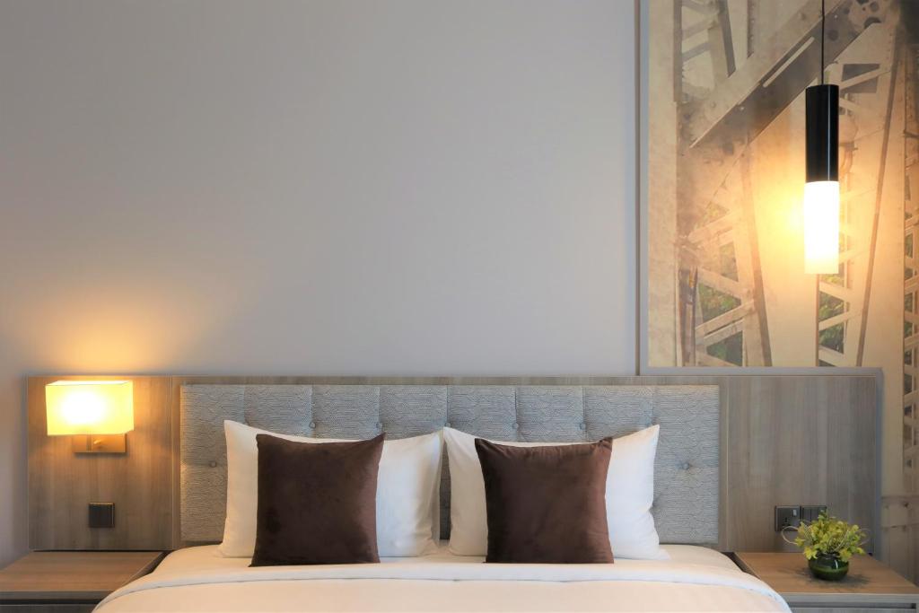 a bed with white pillows and a painting above it at KSL ESPLANADE HOTEL with HOT SPRING in Klang