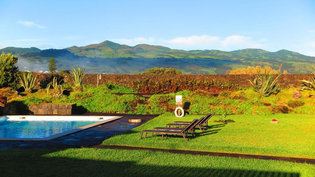 a backyard with a pool and two chairs and a table at Sao Vicente Lodge - Atlantic Retreat in São Vicente Ferreira