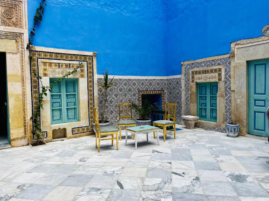 a patio with chairs and a table and blue ceilings at Dar Lekbira Boutique Hôtel in Sousse