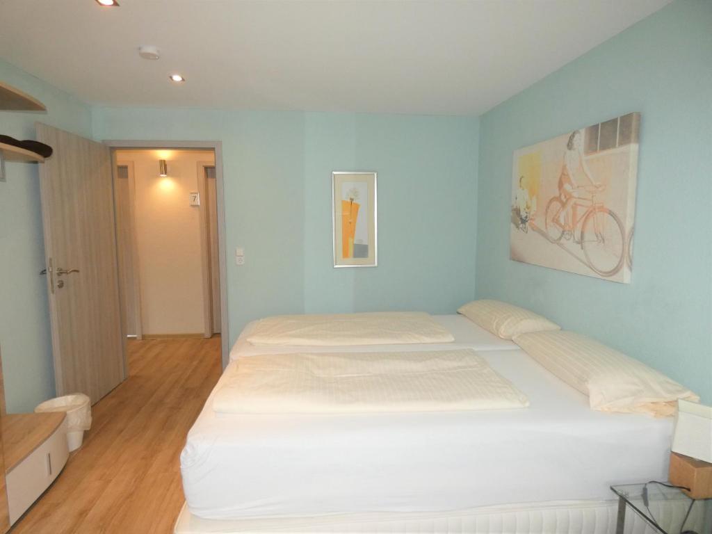 een slaapkamer met een wit bed en een fiets aan de muur bij Hotel Yel in Ludwigshafen am Rhein
