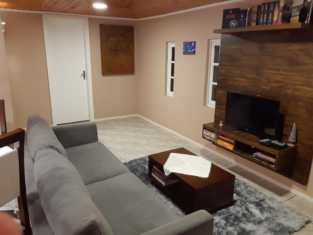 a living room with a couch and a flat screen tv at Rifugio del Camino - Chalé Completo in Gramado
