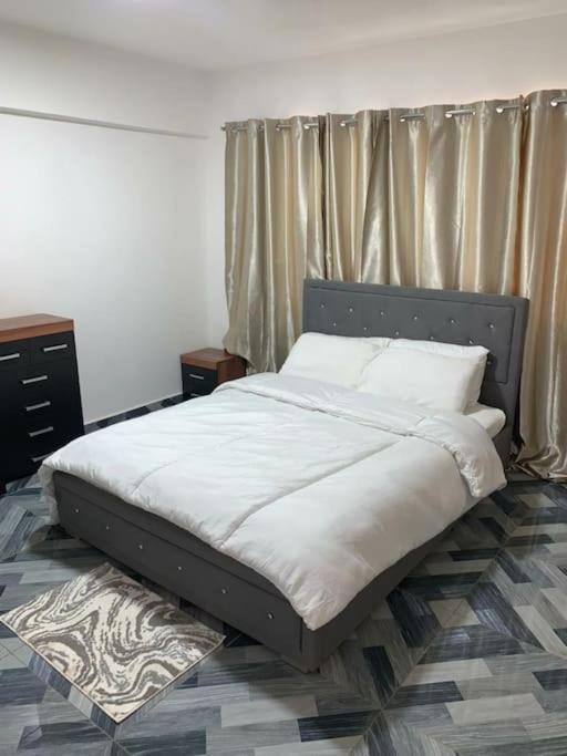 a bed with white sheets and pillows in a bedroom at Lovely 1-bedroom rental unit for short stays. in Tema