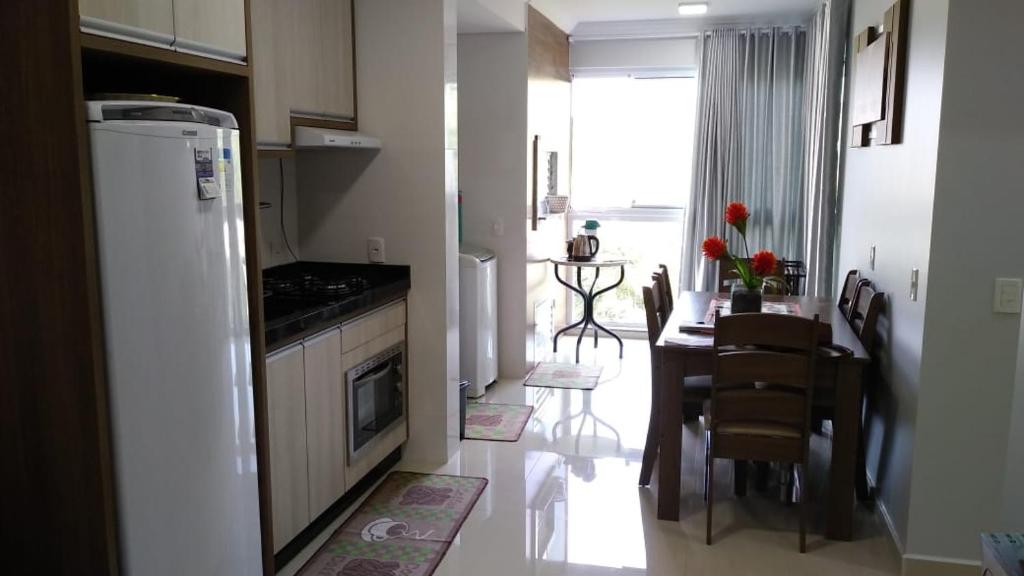 a kitchen and dining room with a table and a refrigerator at APARTAMENTO NOVO E COMPLETO in Piratuba