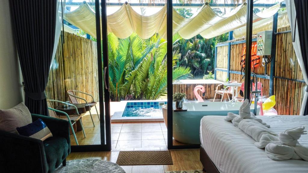 a bedroom with a view of a pool and a tub at Phetrapoolvilla (เภตราพูลวิลล่า) in Surat Thani