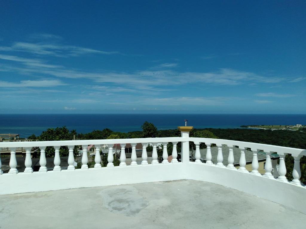 uma varanda branca com vista para o oceano em Valentine's Castle em Saint Annʼs Bay