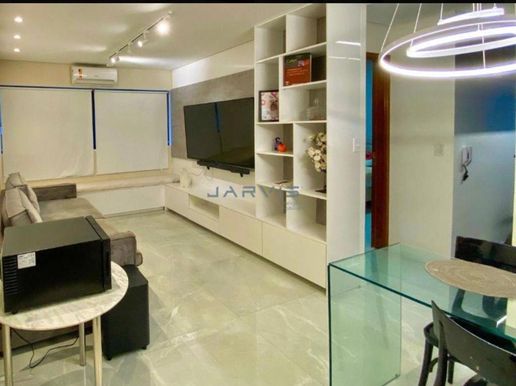 uma sala de estar com uma mesa de vidro e uma televisão em Apt. encantador 50m da praia de Ponta Verde em Maceió
