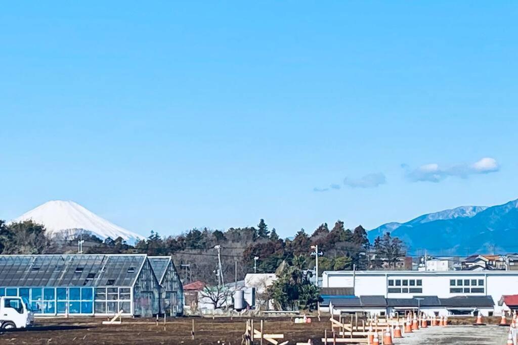 a parking lot with a building and mountains in the background at 湘南の潮風に吹かれて自然豊かな丘ーーー湘南の丘のヴィラ＠ふじさわ in Fujisawa