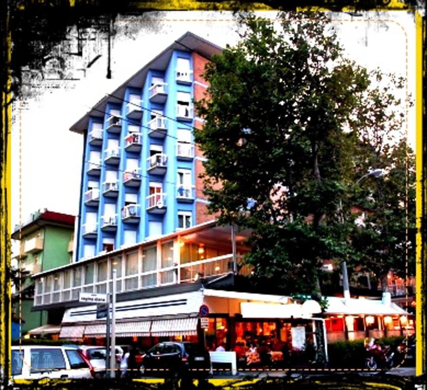 un grand bâtiment bleu avec des voitures garées devant lui dans l'établissement Hotel Galles Rimini, à Rimini