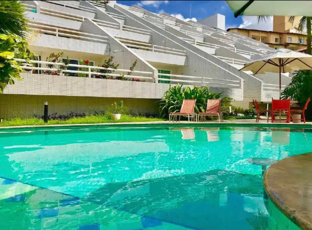 a swimming pool with blue water in front of a building at Varandas - Apartamentos in Natal