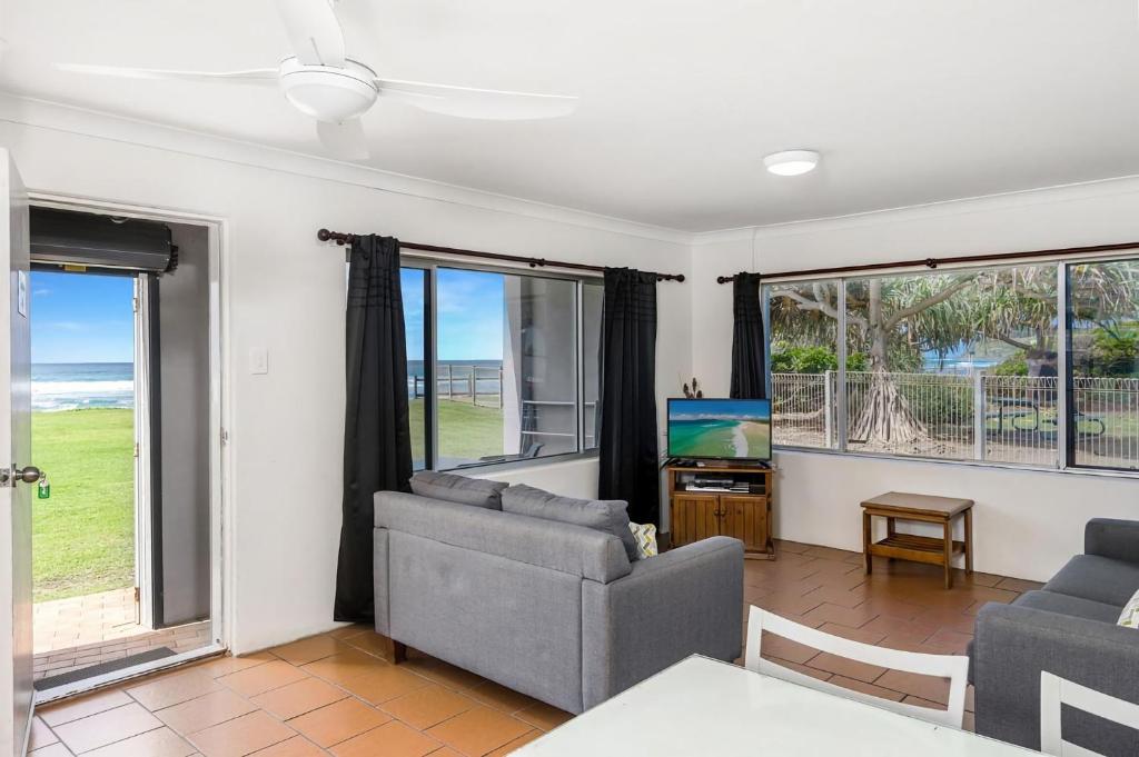 a living room with a couch and a tv and windows at Apartment 4B in Lennox Head