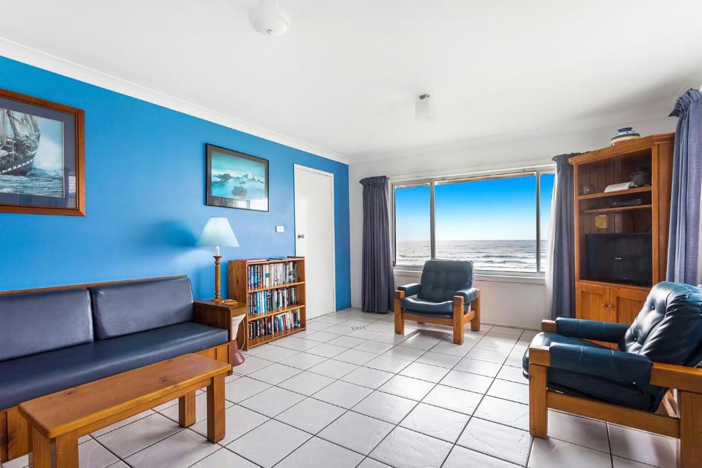 レノックス・ヘッドにあるAbsolute Beachfront Apartments 3Tの青い壁のリビングルーム(ソファ、椅子付)