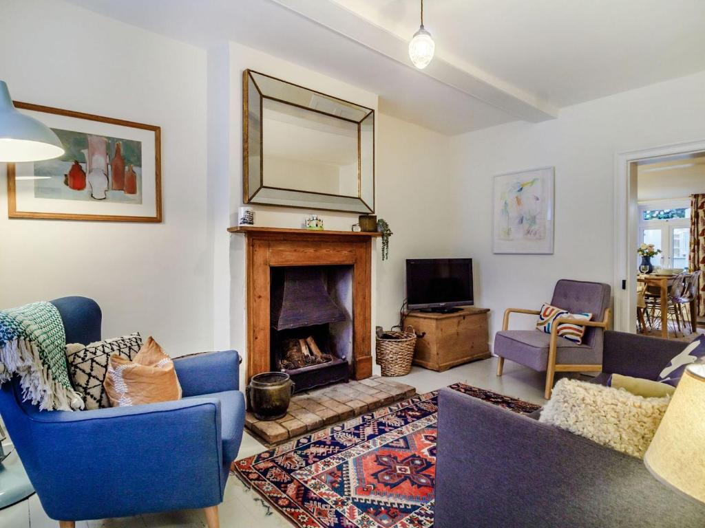 a living room with a fireplace and blue chairs at The Yellow Cottage On The Hill in Framlingham