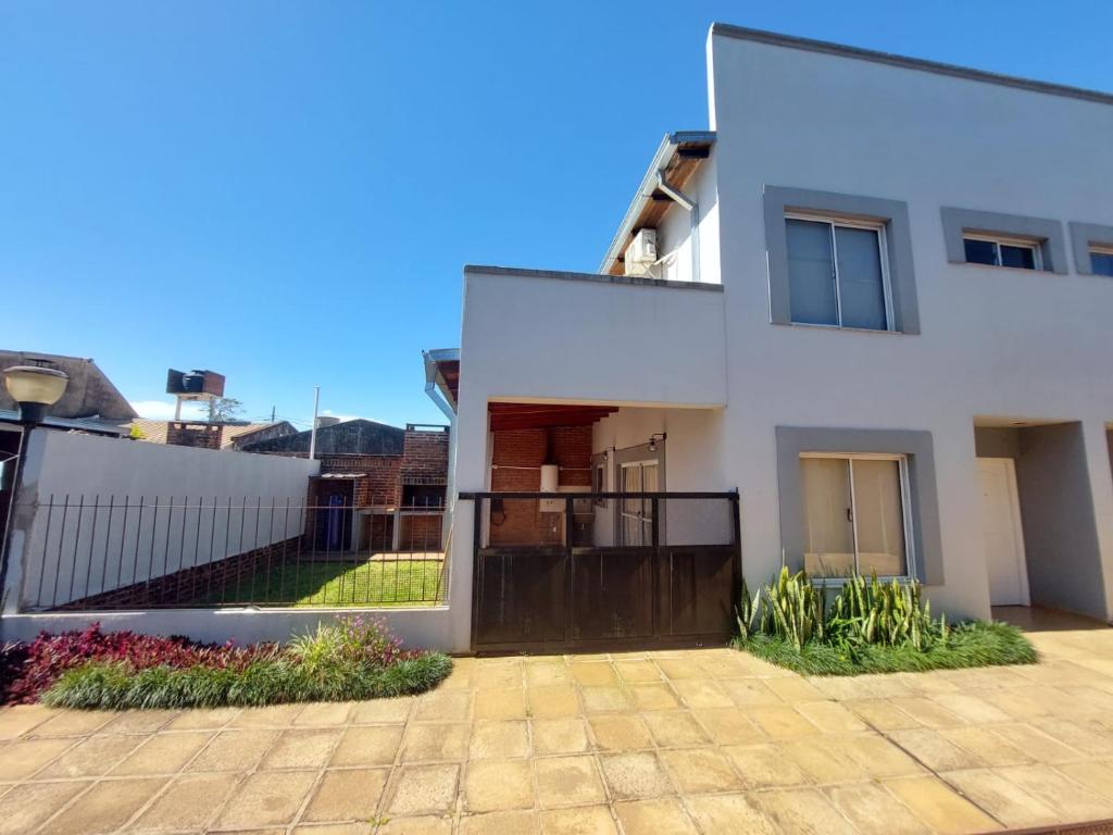 a white house with a fence and a driveway at Hermoso duplex en barrio cerrado in Posadas