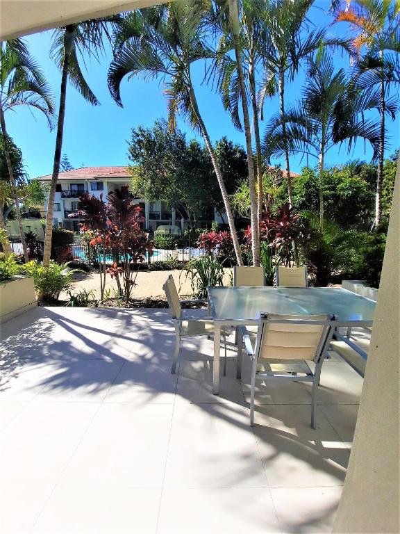 a table and chairs on a patio with palm trees at Luxury Residence Turtle Bay Resort in Gold Coast
