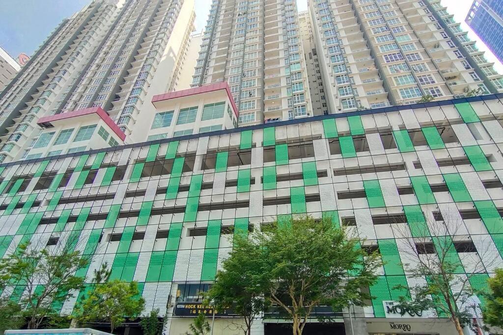 a large building with green windows in front of tall buildings at JB Twin Galaxy Residence near KSL Mall and NewYorkHotel in Johor Bahru
