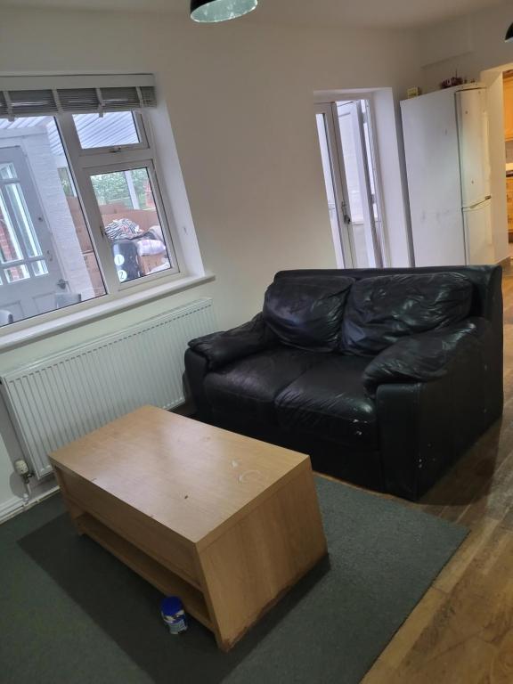 a living room with a black leather couch and a coffee table at No 6 Decent Home (Cozy double bedroom) in Ashton under Lyne