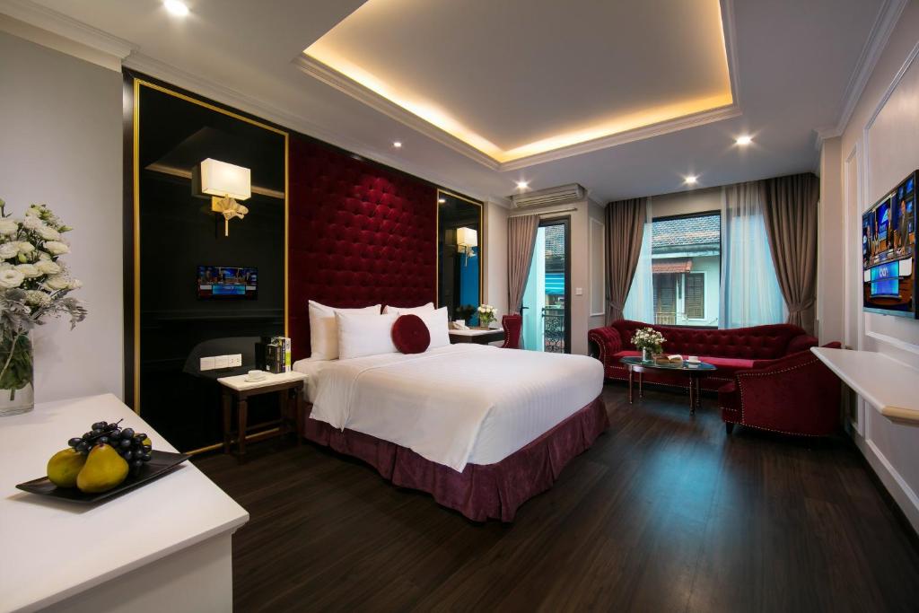 Un dormitorio con una gran cama blanca y una pared roja en Flora Centre Hotel & Spa, en Hanói