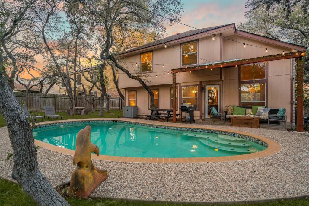 a house with a swimming pool in front of a house at 3B Villa w Pool, BBQ, Firepit, Yard Games, Gym in San Antonio