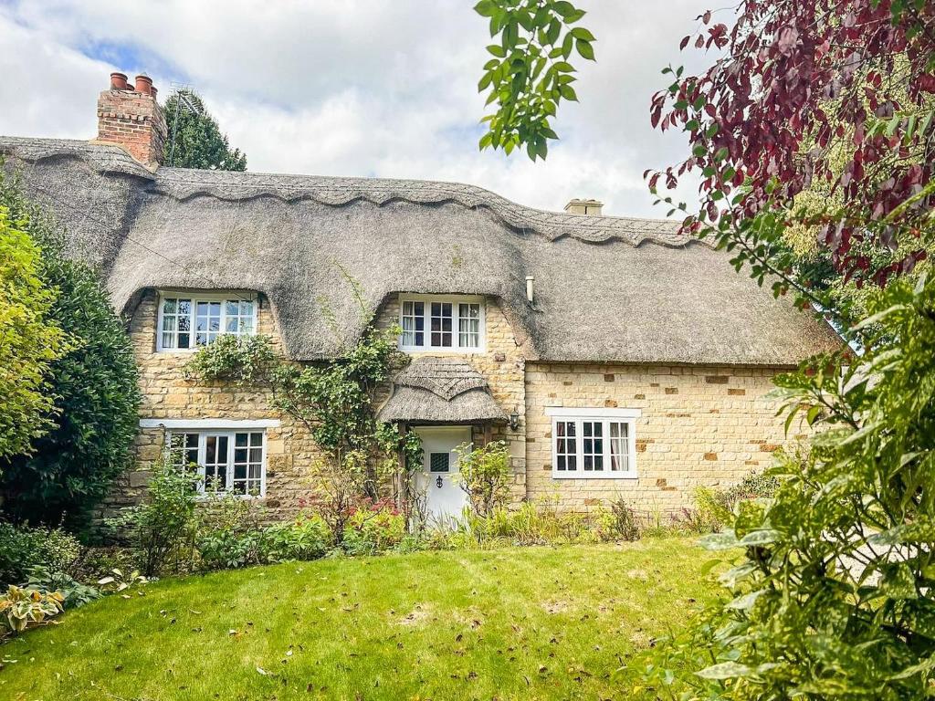 una antigua casa de piedra con techo de paja en Bakers Retreat, en Cottesmore