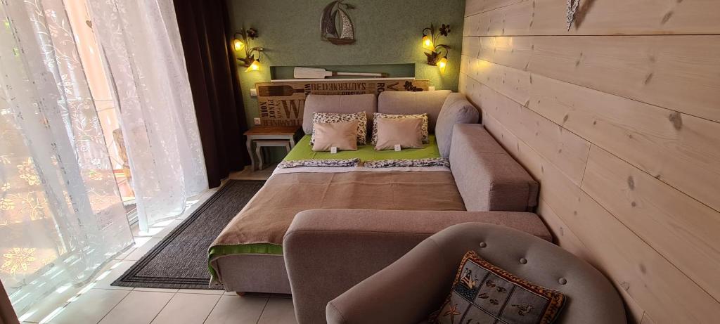 a room with a bed and a couch and a window at Belloapartamento Ház Balatonkenese, Strand 800m, Jakuzzi in Balatonkenese