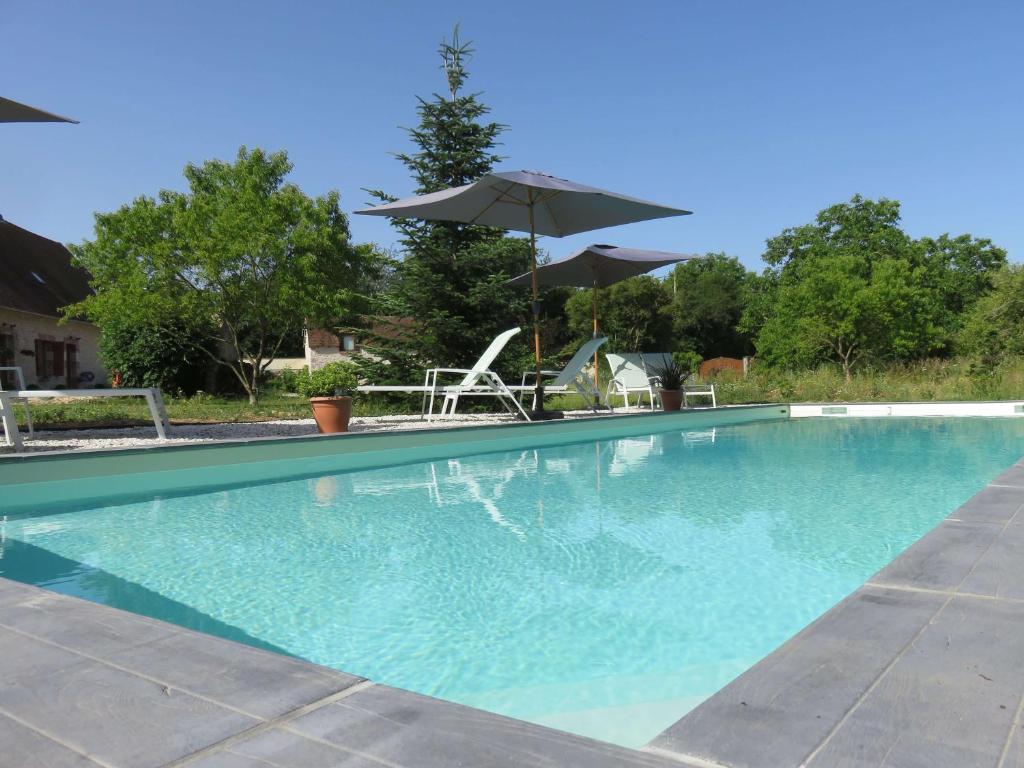 una piscina con sombrilla, mesa y sillas en Chambres d'Hôtes L’Échappée Belle en Saint-Brisson-sur-Loire