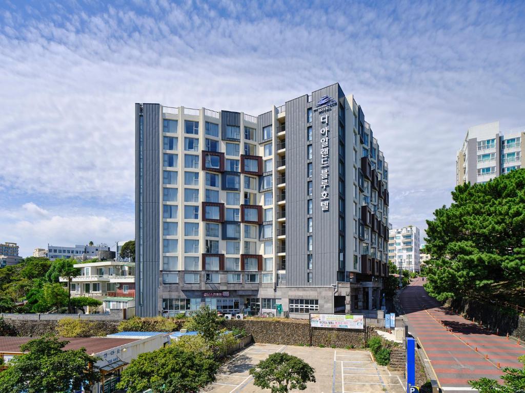 un edificio de apartamentos alto en medio de una ciudad en The Island Blue Hotel, en Seogwipo