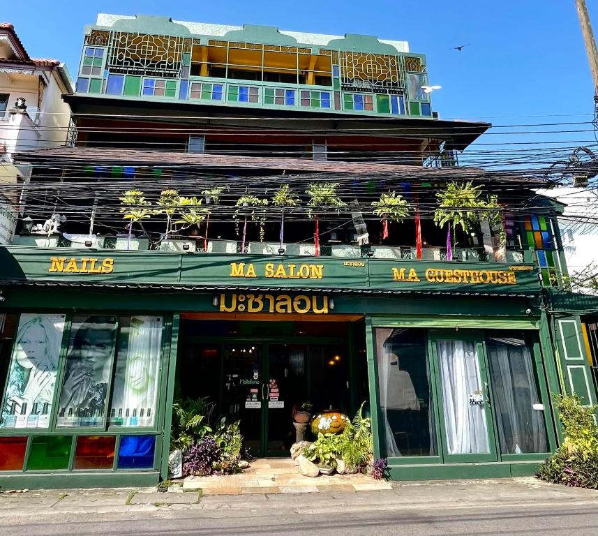 a green building with plants on top of it at Ma Guesthouse Chiang Mai in Chiang Mai