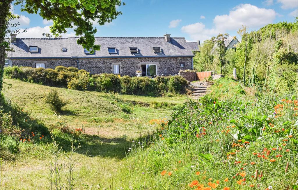 une maison en pierre sur une colline avec un champ de fleurs dans l'établissement Beach Front Home In Plouezec, à Plouézec