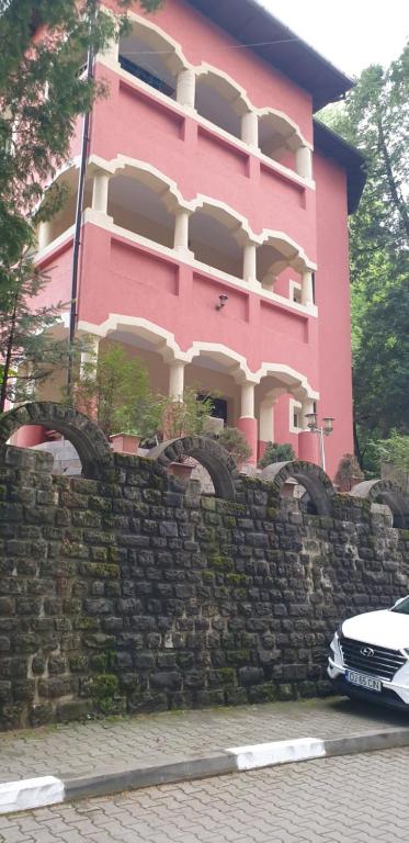 a pink building behind a stone wall at Casa Rosa in Băile Olăneşti