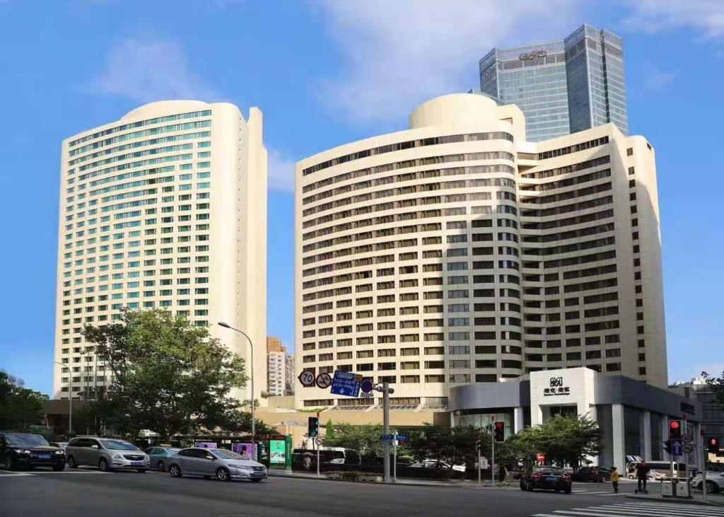 two tall buildings with cars on a city street at Furama Hotel Dalian in Dalian