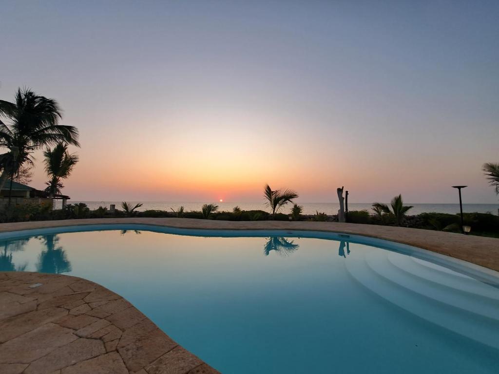 a swimming pool with the sunset in the background at Aux 2 Métis in Toliara