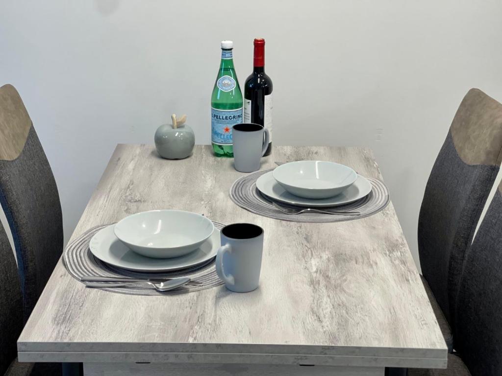a wooden table with two plates and two bottles of wine at Central apartment in Vilnius