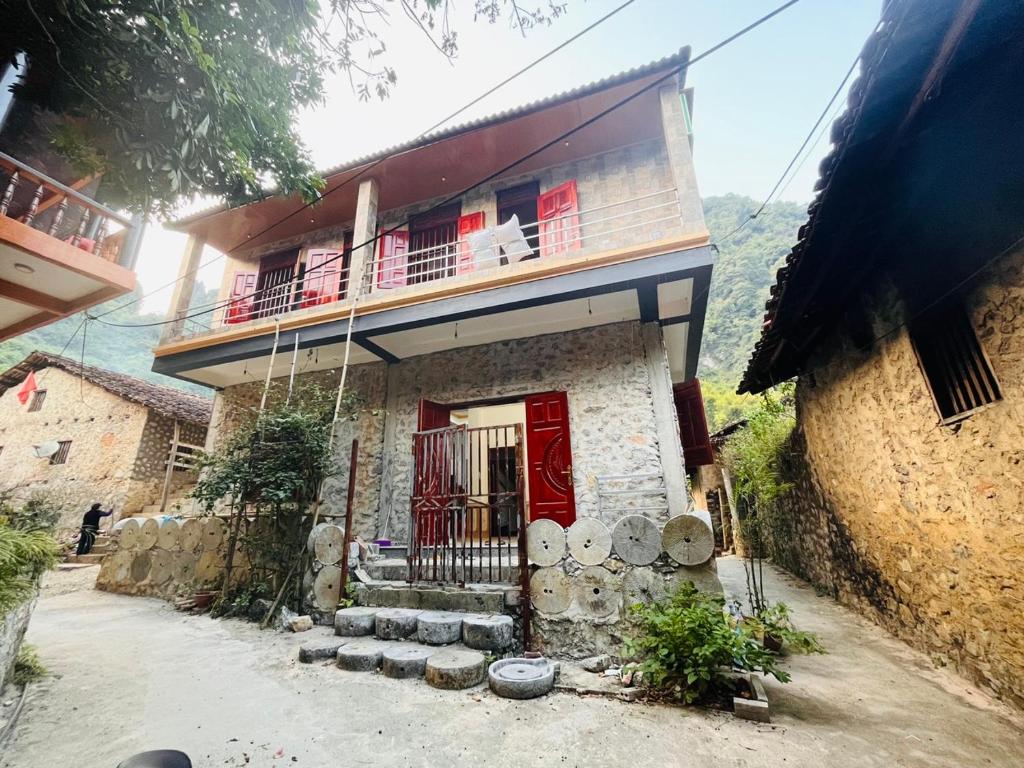 een huis met een rode deur en een balkon bij Homestay Bản Giốc- Tay's Traditional Village in Cao Bằng