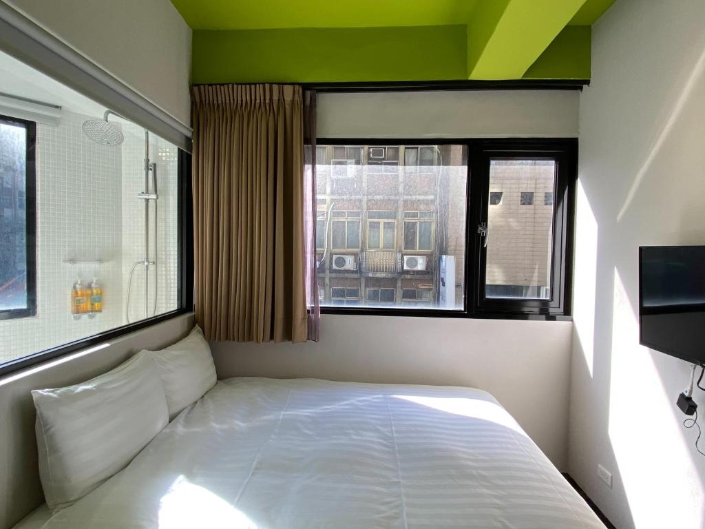 a bedroom with a white bed and a window at Cho Hotel in Taipei