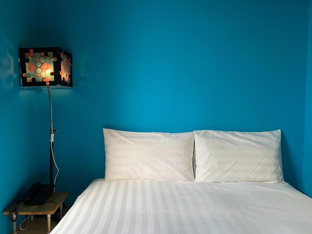 a blue bedroom with a white bed with a blue wall at Cho Hotel in Taipei