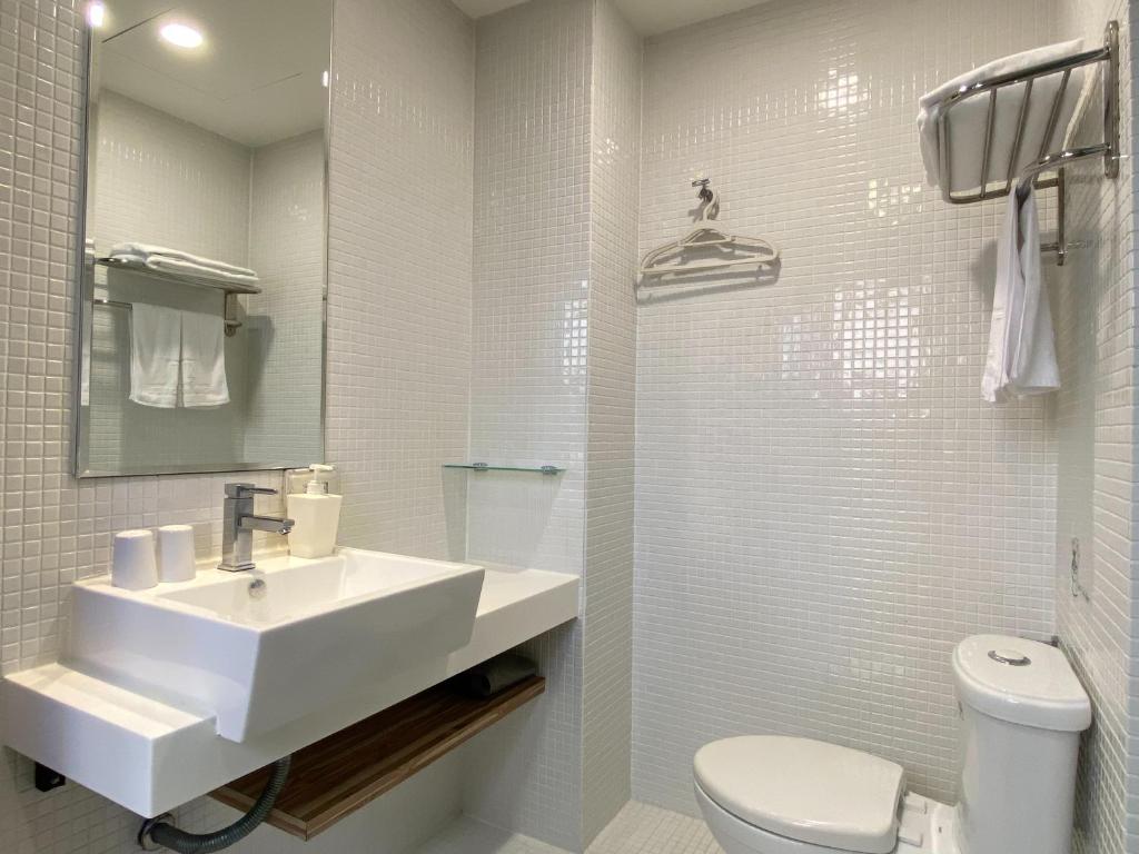 a white bathroom with a sink and a toilet at Cho Hotel in Taipei